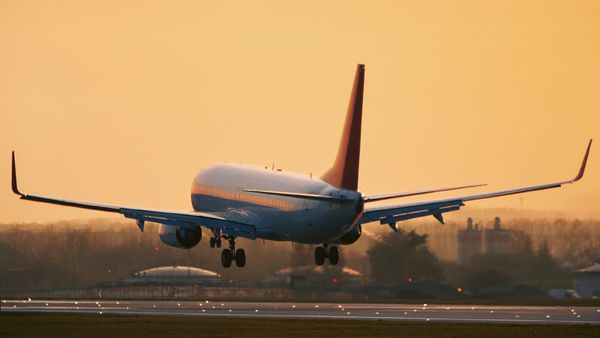 Commercial jet flying near a runway at sunset